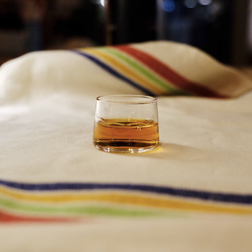 TINI The Sip with a pour of whiskey on a striped linen